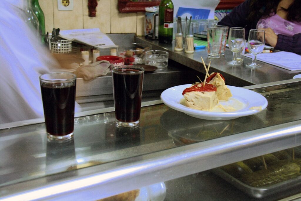 Racion de atun acompañado con vino servidos como pasapalo en una tasca.