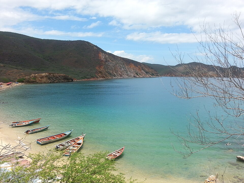 Bahía del Parque Nacional Mochima con aguas turquesas, montañas y botes de pescadores en la orilla