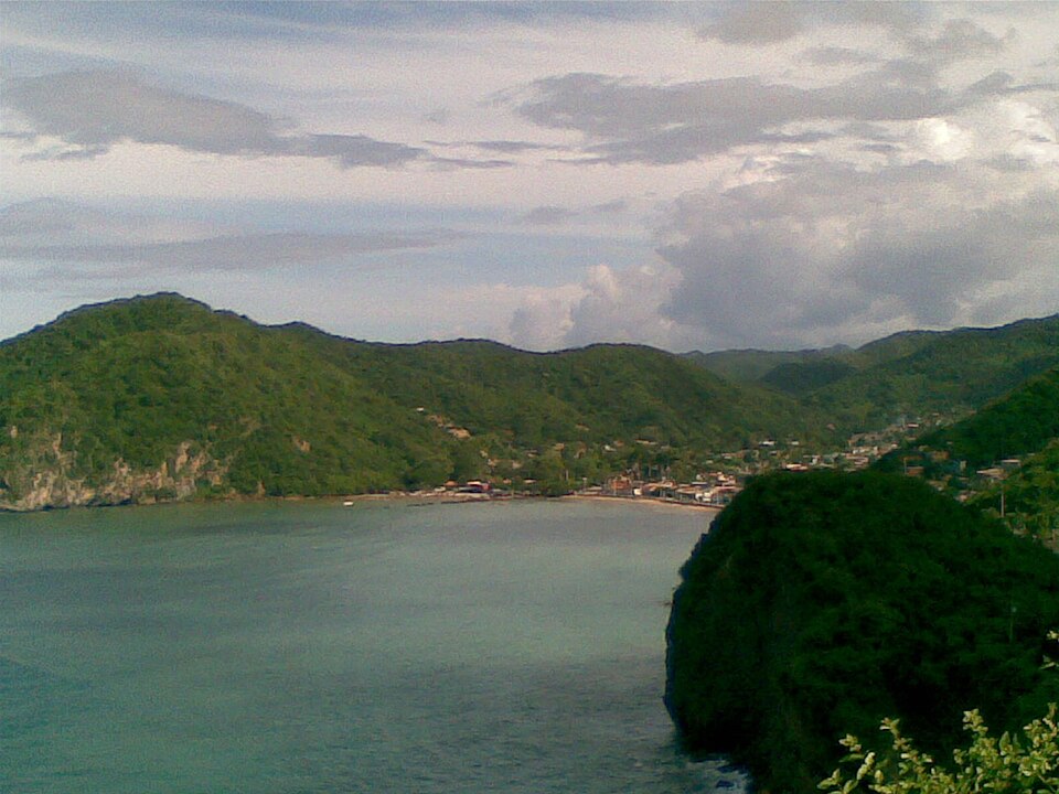 Bahía de Río Caribe, Sucre, Venezuela, rodeada de colinas verdes y aguas turquesas, región productora de cacao floral y frutal.