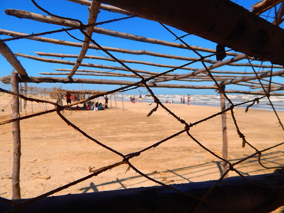 Visitantes disfrutan de la playa de la Isla de Zapara bajo estructuras rústicas frente al mar en el estado Zulia.
